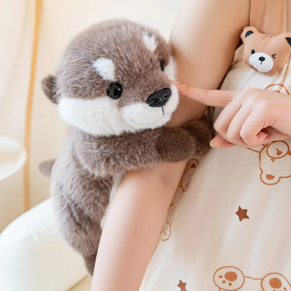 doudou loutre marron blanc sur bras