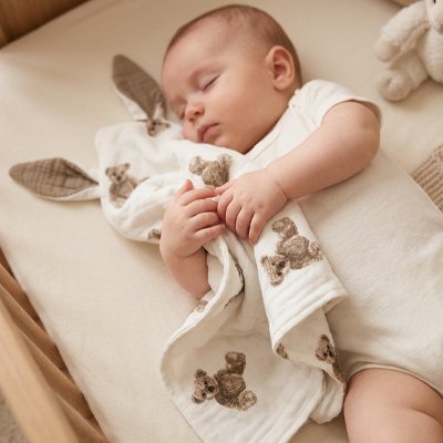 Doudou ourson assis avec bébé dormant