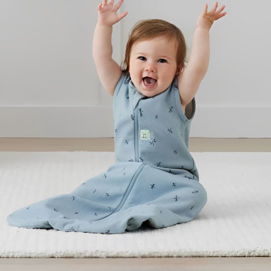 Gigoteuse bleu imprime sur bebe assis sur tapis