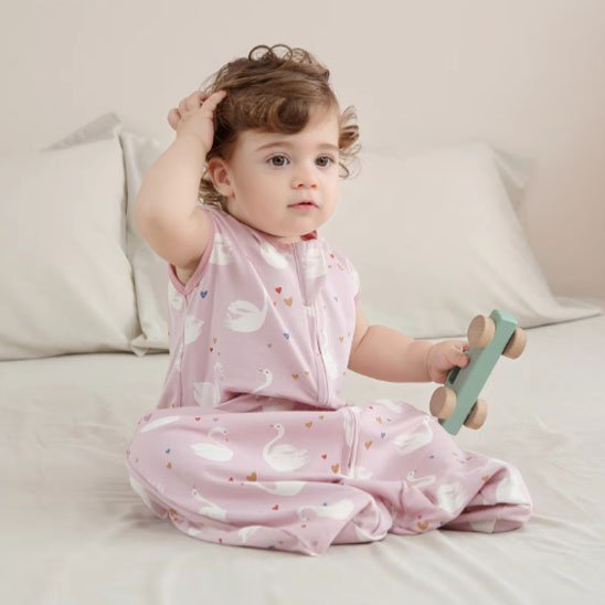 Gigoteuse rose imprimé sur bébé fille assis sur lit